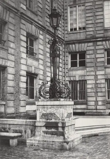 Photo 2: Exterior · Single lamp on elaborate wrought iron lamp stand, mounted on stone plinth