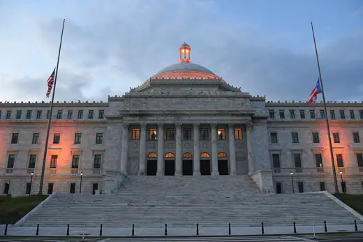 Photo 4: Exterior · Rear (south) façade of Capitol of Puerto Rico overlooking San Juan Bay at dusk with flags at half mast