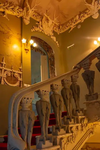 Photo 5: Interior · Grand concrete staircase with eagle balusters and a red carpet inside the historic House with Chimaeras