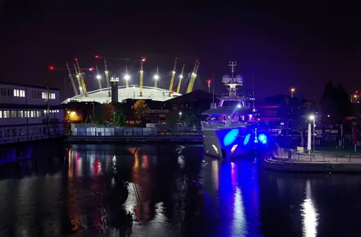 Photo 3: Exterior · The yacht Kamalaya (IMO 1012103), berthed in Canary Wharf and bathed in blue light after dark