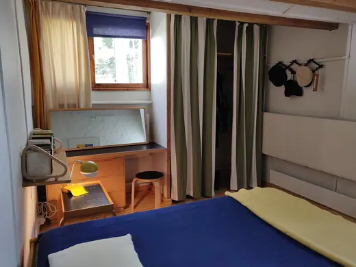 Photo 5: Interior · A small room that has bed, tiny window and a desk