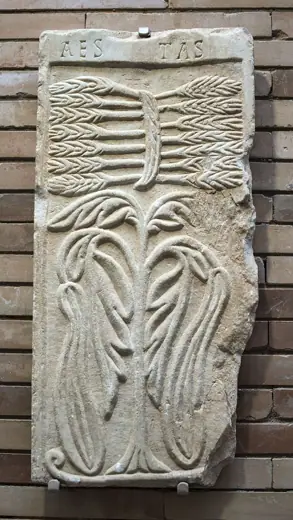 Photo 4: Exterior · Tablero de mármol de unos 70 cm de altura con un árbol y un haz de espigas