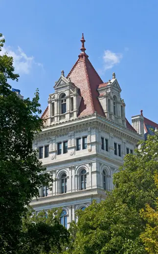Photo 2: Exterior · One of the two main towers of the New York State Capitol building, framed by the trees around it